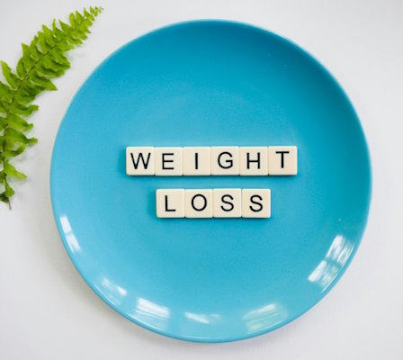 Leerer blauer Teller, mit Buchstaben ausgelegt auf denen 'Weight Loss' steht